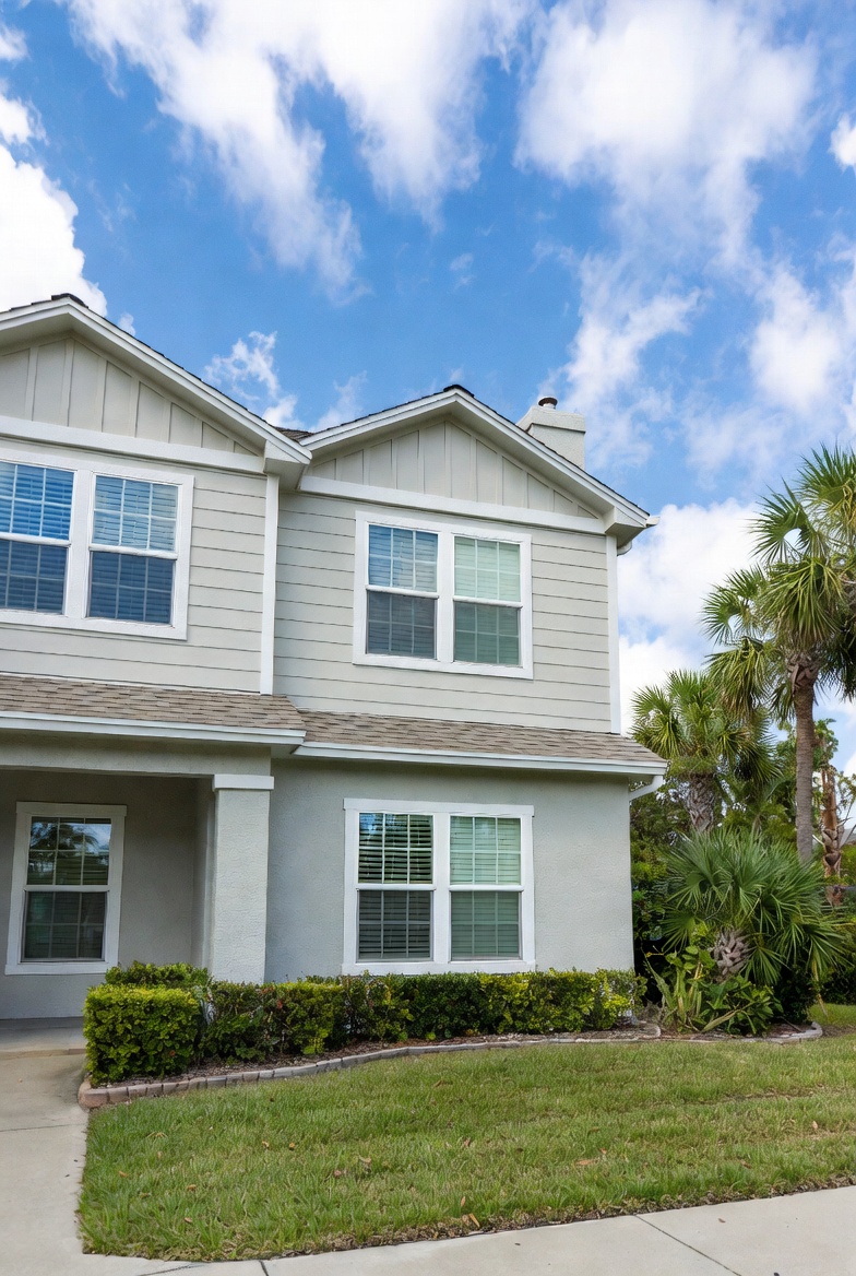 Exterior view of modern suburban home in Central Florida featuring multiple white double hung replacement windows, sunny daylight and palm trees